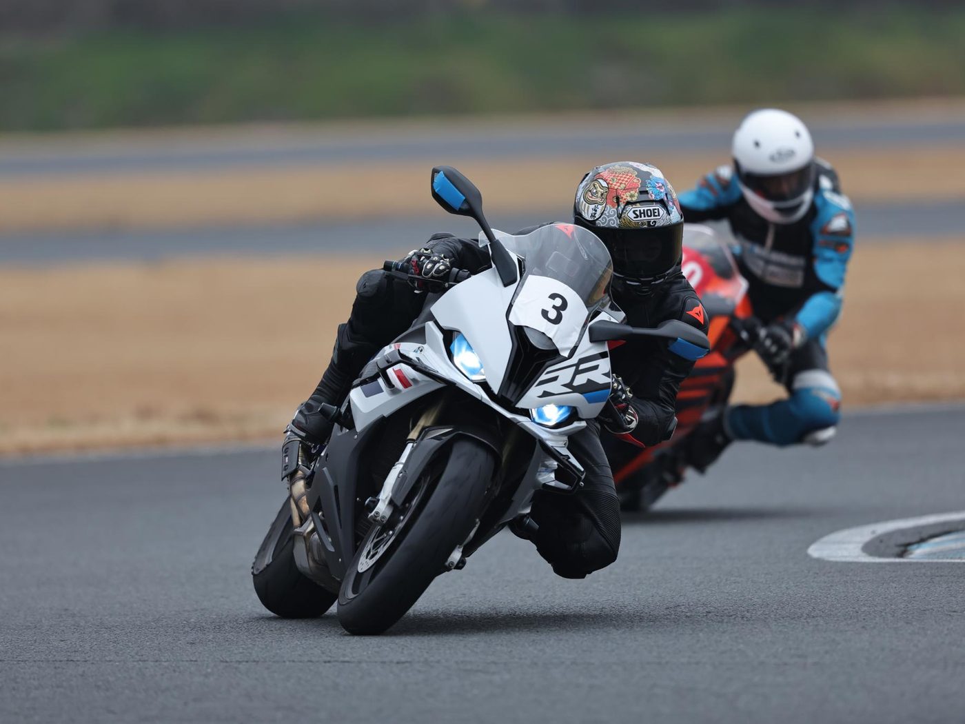2台の参加者がバイクを倒し込み、コーナーを走行する様子